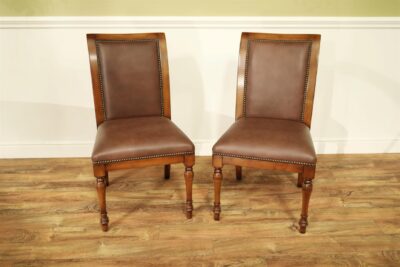 Solid walnut and leather upholstered dining chairs with brass tacks